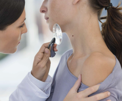 dermatologist reviewing mole on female patients neck