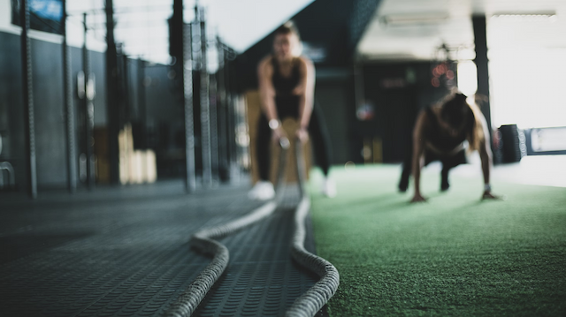 Two people training in a gym using ropes